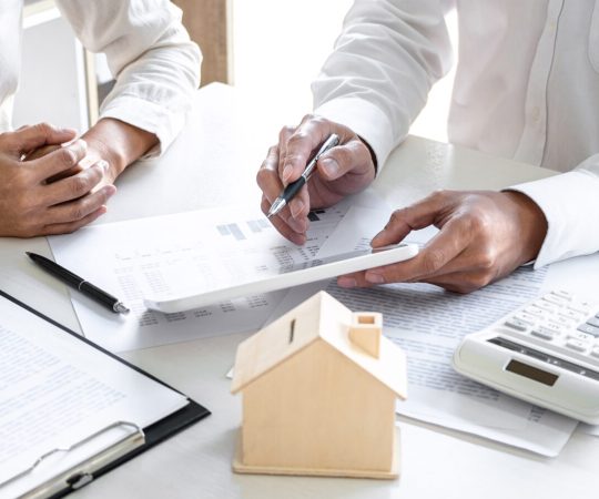 Real estate broker agent presenting and consult to customer to decision making sign insurance form agreement, home model, concerning mortgage loan offer for and house insurance.